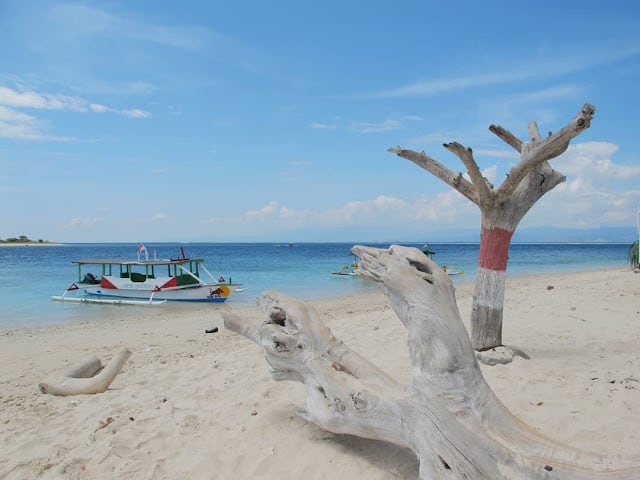 Pasir putih, batu karang dan perahu disekitar garis pantai Gili Kondo