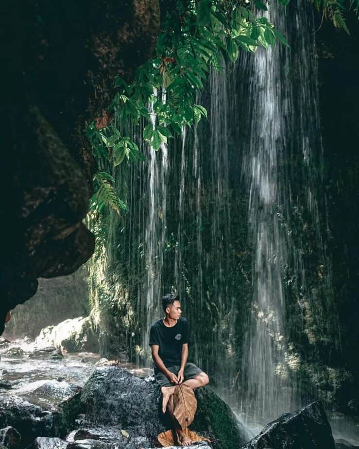wisatawan berdiri diselah selah air terjun Batu Janggot