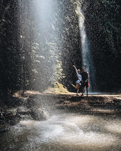 Dua orang wisatawan terlihat ceria bermain air di Air Terjun Benang Stokel
