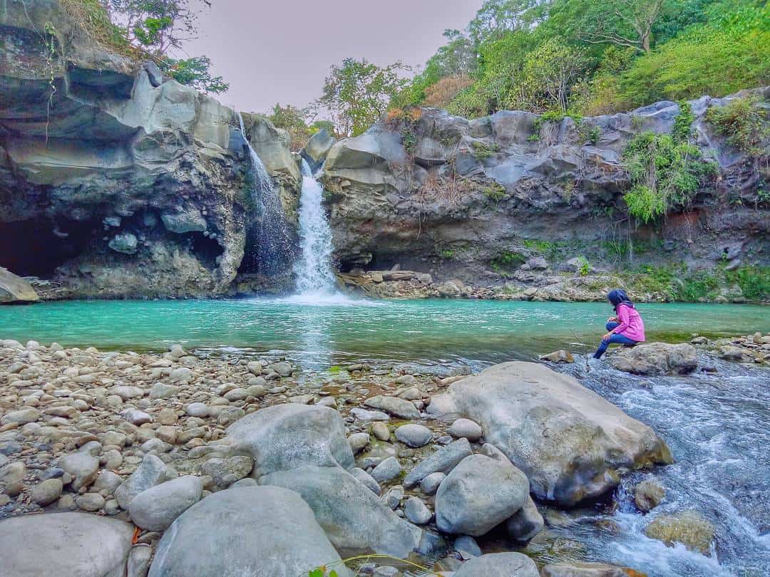 wisatawan duduk di batuan pinggir kolam Air Terjun Umar Maya