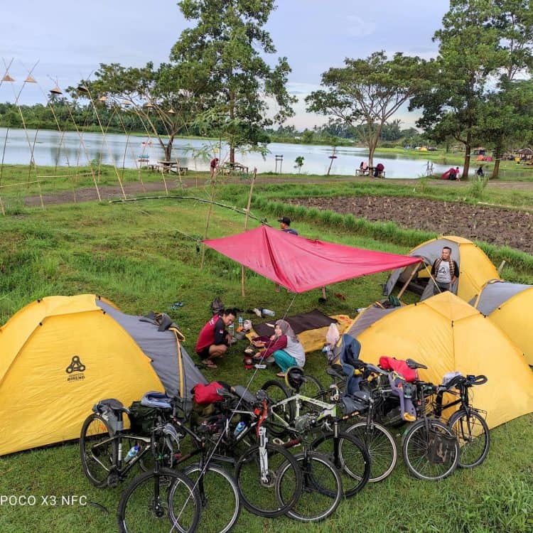 Pemandangan wisatawan camping di pinggir danau dengan sepeda yang berderet