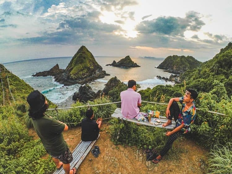 Wisatawan duduk diatas Bukit Telawas sambil memandangan laut dan Pantai Telawas