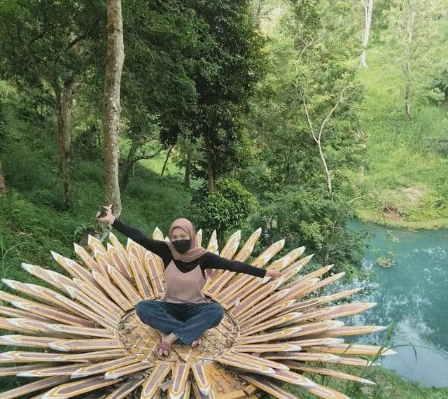 Seorang wisatawan berfoto di spot foto cantik yang terbuat dari kayu