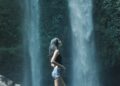 Wisatawan berdiri di depan air terjun yang indah