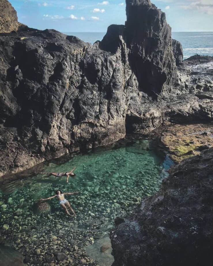 Wisatawan berenang di kolam alami yang terbentuk di tepian laut Pantai Nambung