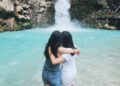 Dua perempuan melihat keindahan air terjun