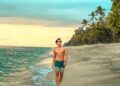Wisatawan laki laki berjalan di pinggir Pantai Mangsit