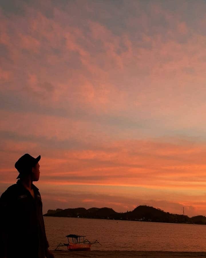 Wisatawan pria menikmati keindahan sunset di Pantai Batu Berang