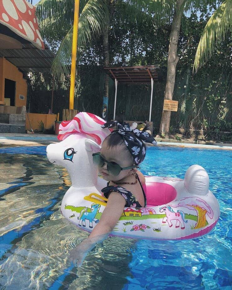 Balita bermain air dengan ban karet unicorn