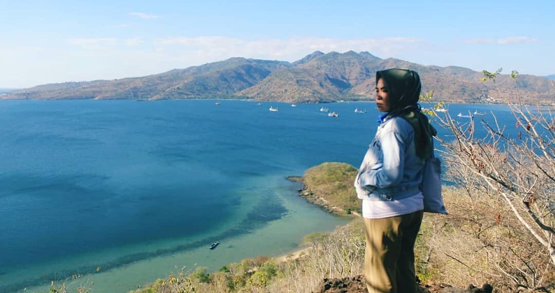 Wisatawan menatap ke lautan di atas puncak bukit Pulau Kambing