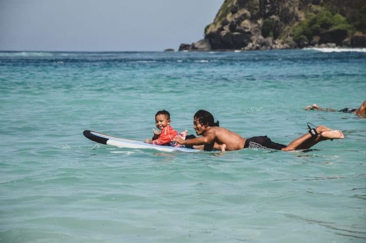 Wisatawan berselancar bersama anak di Pantai Tropical