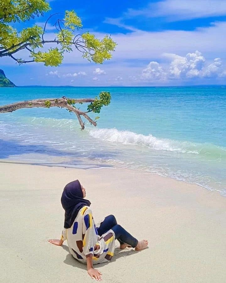 Wisatawan duduk di atas pasir putih tepi Pantai Jelenga