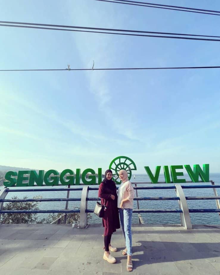 Dua wisatawan berada di tepi tulisan Senggigi View