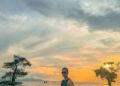 Seorang pria melihat suasana sunset di tepi Pantai Ai Lemak