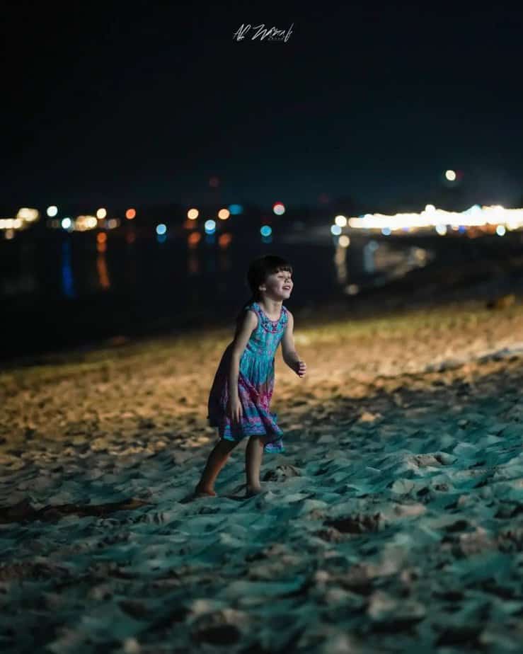 Anak kecil perempuan berlarian di Pantai Jimbaran malam hari