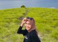 Wisatawan berswafoto dengan latar padang rumput yang hijau segar
