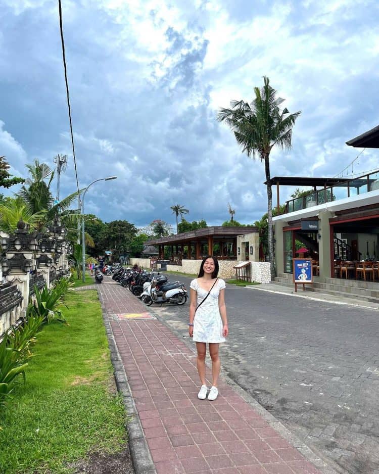 Wisatawan perempuan dengan baju putih berada dikawasan cafe Pantai Legian