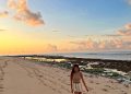 Wisatawan perempuan berjalan di tepi pantai ketika menjelang sunset