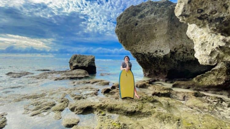Wisatawan berdiri di tepi batuan karang pantai