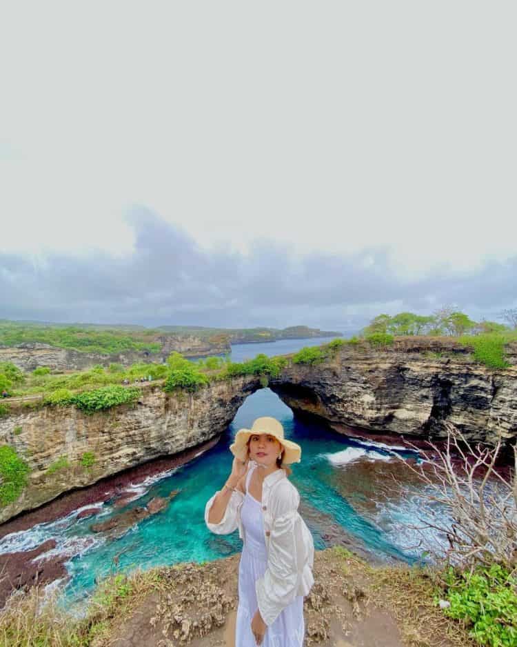 Wisatawan berfoto dengan latar belakang batuan karang yang berlubang