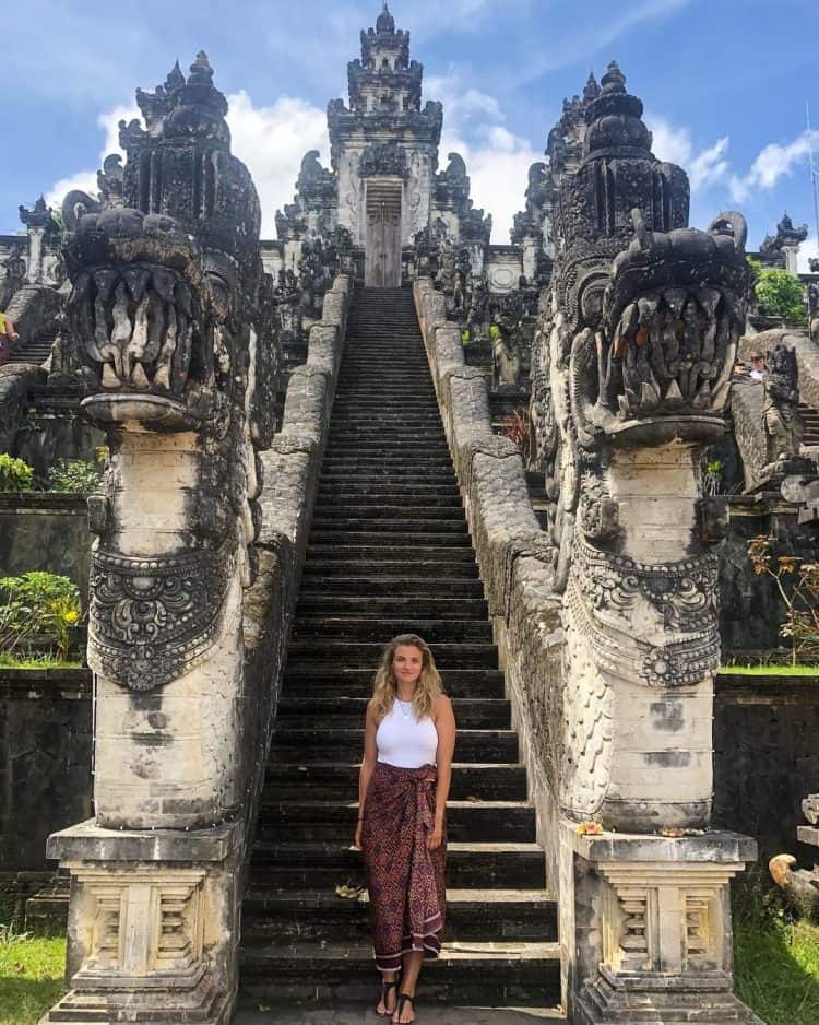 Wisatawan asing berdiri di depan anak tangga Pura Lempuyang